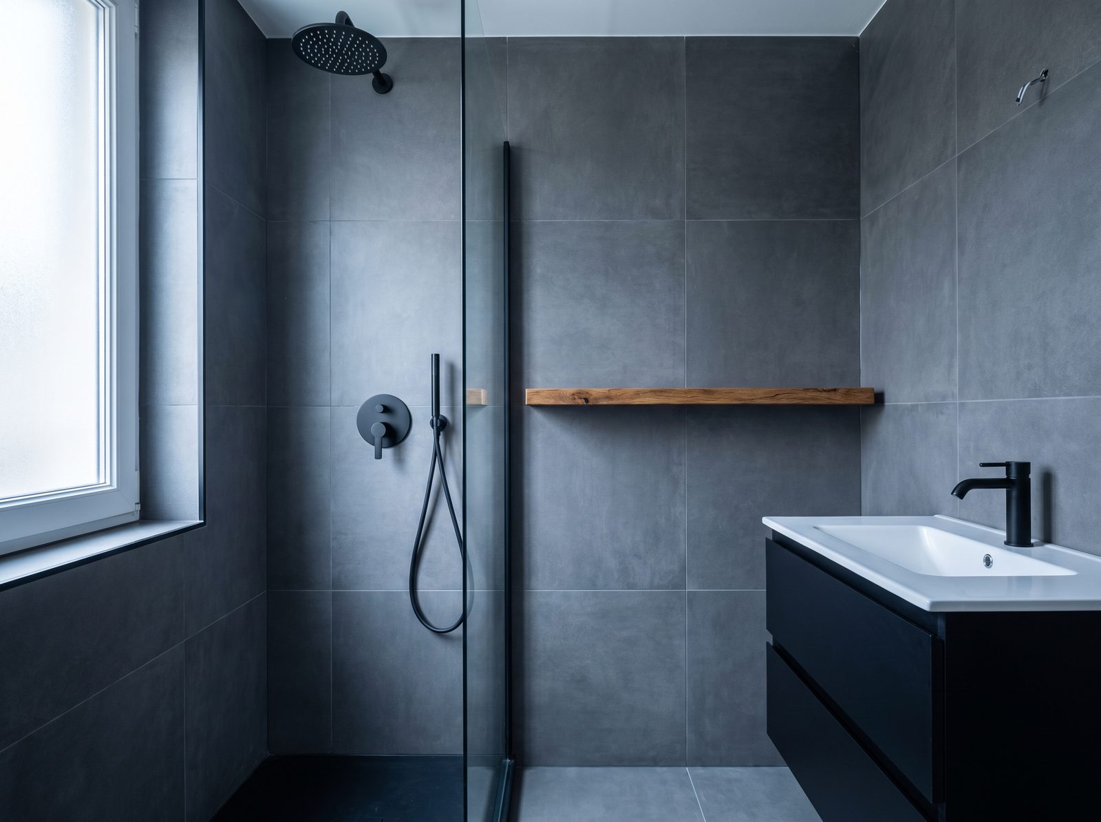 Salle de bain rénovée : grande dalle grise, robinetterie noire, douche à l'italienne